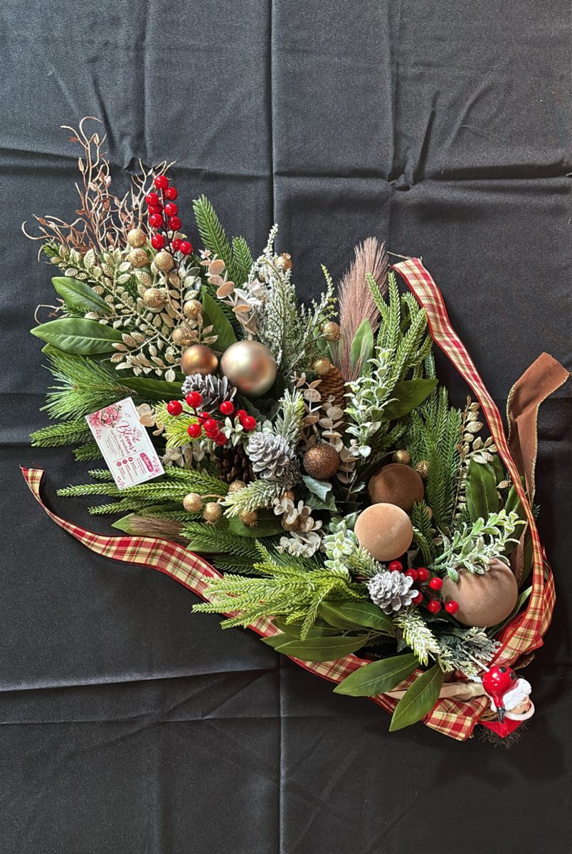 Christmas door swag of pine, gold baubles, berries and pine cones wrapped in tartan ribbon